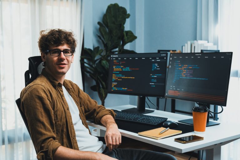 Développeur web travaillant sur du code avec plusieurs écrans dans un bureau moderne